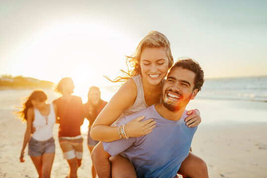 Young and diverse group of friends walking on a sandy beach on the ocean