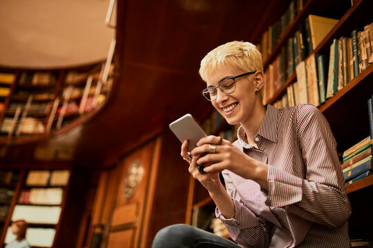 Young caucasian female student using a smart phone while studying in a university library
