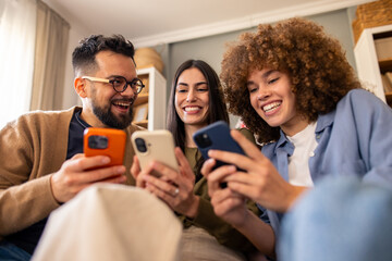 Multiethnic Group Of Young Adults Sharing Social Media Content And Laughing On Comfortable Living Room Couch