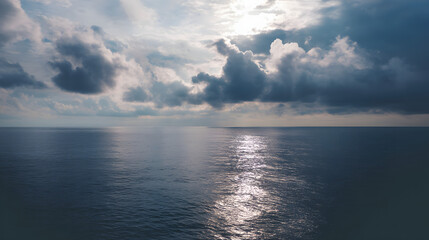 Obraz premium Bright morning on a calm ocean with fluffy clouds reflecting on the water surface in a serene coastal setting