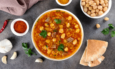 Moroccan harira soup with ingredients, spices and arabic bread on grey background. Top view. Ramadan iftar food.