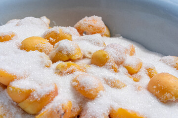 Peaches being preserved with sugar in a bowl for homemade preserves during summer