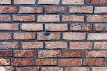 Textured brick wall with a mix of red and brown tones in urban setting