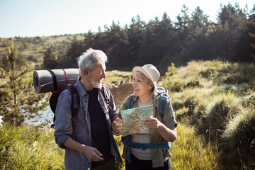 Senior couple hiking together and reading a map outdoors in nature