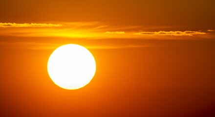Fiery Globe: Sun Sets Amidst Ominous Orange Sky with Wispy Clouds at Dusk, Casting a Blazing Glow in Nature's Golden Hour Spectacle