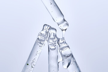 Four different face serum pipettes on a neutral background.