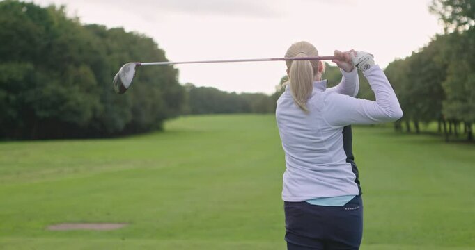 Swing, woman or athlete playing golf for fitness, workout or exercise with a driver on a green course. Wellness, girl golfing or golfer training in action or sports game driving with a club stroke