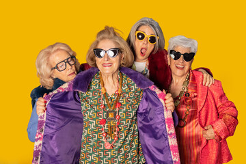 Group of stylish senior women showing fashion and attitude on yellow background