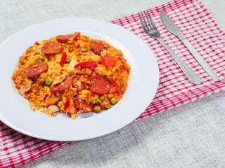 Fine tasty Spanish paella dinner with rice and high quality chorizo sausage on white plate and simple table runner. Mediterranean style dish. Popular food made from premium ingredients.