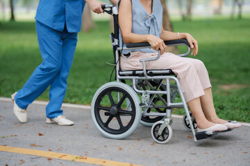 Obraz premium Elderly woman in wheelchair with nurse in park
