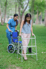 Fototapeta premium Asian female doctor examines disabled elderly patient in wheelchair at paralyzed elderly park. Treatment and therapy. Health care.