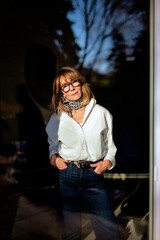 Portrait of a mature woman standing in living room photographed through window