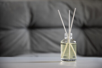 Aromatherapy reed diffuser bottle with fragrance oil and sticks on a gray blurred background. Home interior. Wellness and relaxation