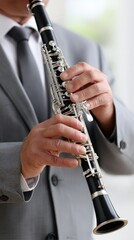 Fototapeta premium Close-up of hands skillfully playing the clarinet in a grey suit on a white background focusing on musical performance and artistry