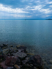 Serene waterscape with sailboat gliding under a soft sky, calm sailing ambiance with tranquil reflections