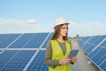 Young Female Engineer with Tablet Inspecting Rows of Solar Panels at Outdoor Farm, Left Profile, Focused.