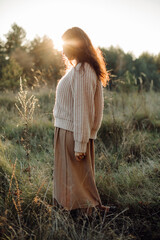 Young woman enjoying golden hour sunlight in a meadow at sunset
