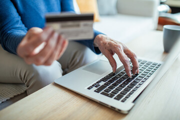 Senior woman shopping online with credit card and laptop at home