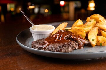 succulent dish of beef mignon with bbq wine sauce and rustic potatoes with blurred restaurant in...