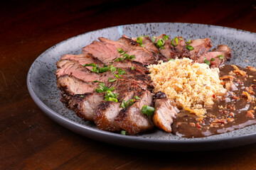 beef sirloin steak cut into strips served with farofa and wine sauce close-up