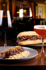 dinner paired with meat dishes of duck magret and duck sandwich with bacon in blurred restaurant with wine and cocktail