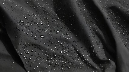 Close-up of Water Droplets on Black Waterproof Fabric with Textured Wrinkles