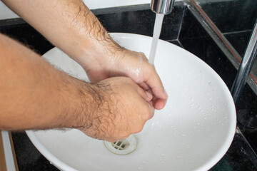 Man washing his hands in the bathroom sink