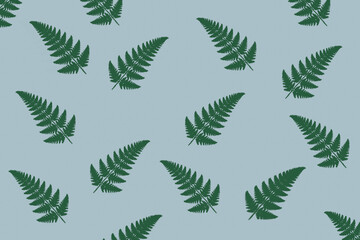 Powtarzający się wzór z zielonymi liśćmi paproci na niebieskim tle, roślinny motyw o prostym układzie i dekoracyjnym charakterze