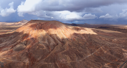 Naklejka premium Dramatic aerial image of the Barranco Ravine near Montana Roja volcanic mountain landscape after a Rain Storm Water river stream near Corralejo in Fuerteventura Canary Islands Spain 