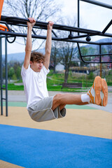 Young Man Doing Hanging Leg Raise Workout Outdoors. Athletic man performs hanging leg raises on an outdoor fitness bar