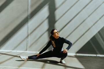 Stretching exercise in a minimalist space with striking shadows at midday