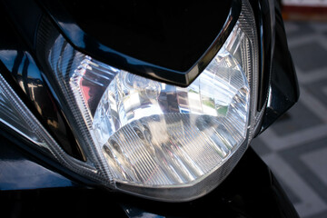 Close up of the main headlight design on an automatic scooter, showcasing the modern and angular shape of the lamp housing