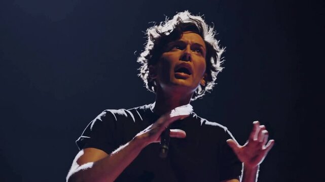 Male performer standing barefoot under dramatic theater spotlight