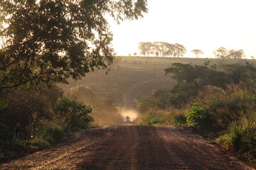 carro trafegando em estrada de terra com luz dourada do nascer do sol 