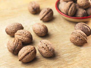 Close-up walnuts in shells lie on wooden table surface. Selective focus. Super foods concept.