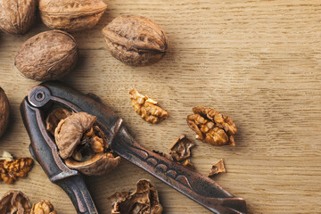 Metal old nutcracker cracks a nut, walnuts in shell, cracked, shell and kernels close-up lie on a...