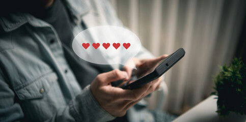 Hands holding a smartphone displaying a speech bubble filled with red hearts for feedback from customer review, satisfaction service experience and business survey
