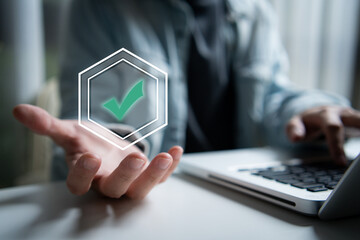 Hand holding digital check mark icon, representing online verification, security approval, and success in a digital technology environment.