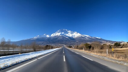 Naklejka premium Highway leading to snow-capped mountain