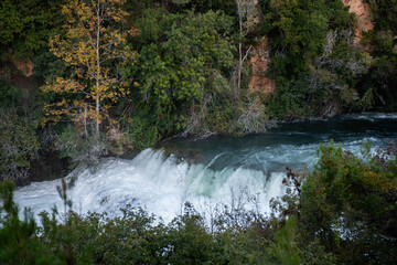 Lush vegetation frames the cascading waterfalls of Krka national park in Croatia, creating a...