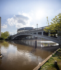 Wide concrete arch bridge spanning a river, reflecting in the water, and trees on the bank.