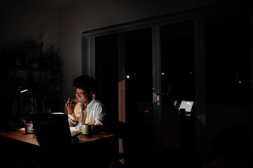 Smiling young African businesswoman talking on a phone in her office at night