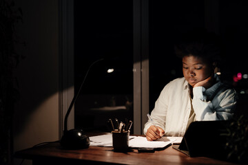 Young African businesswoman working late in her office at home