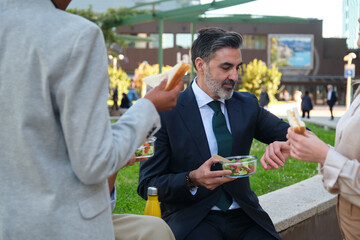 Business colleagues eating healthy lunch outdoors during their office break
