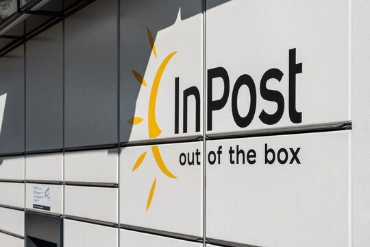 InPost parcel locker exterior with company logo and slogan on white panels during daylight, Poland, modern urban delivery service infrastructure