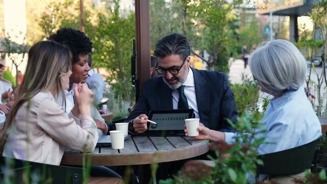 Business colleagues discussing over digital tablet during a meeting at outdoor cafe