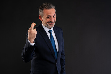 Smiling businessman with crossed fingers gesture.