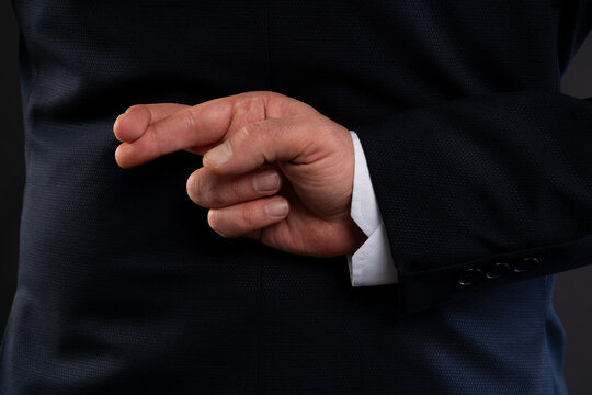 Close-up of hand with crossed fingers behind back.