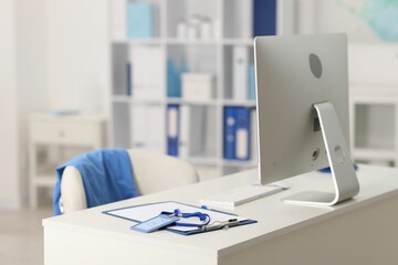 Doctor's workplace with stethoscope, paperwork and computer on desk. Space for text