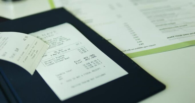 Small check with prices for dishes and total amount lies on bill folder put on table. Receipt symbolizes end of event and preparation for payment process 